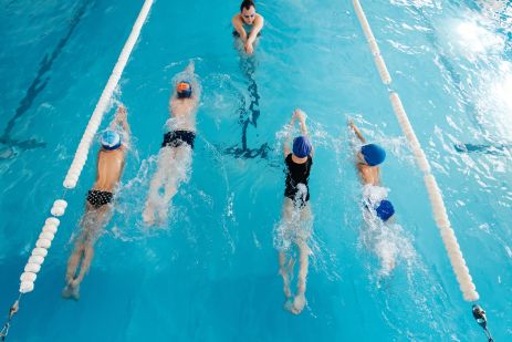 a group of boys and girls train and learn to swim in a modern swimming pool with an instructor. development of children's sports. healthy parenting and promotion of children's sports